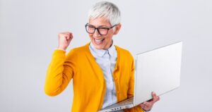 Woman holding computer and cheering for success