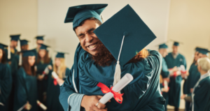 Two graduating students hugging as they wear their graduation gowns and caps