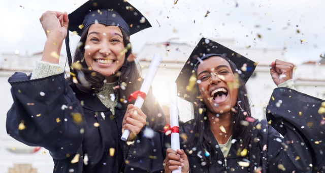 Two students with confetti and graduation gowns and cap on