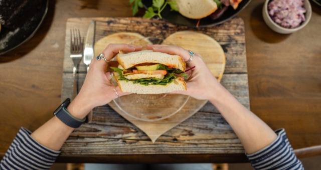 Person eating a sandwich and holding it