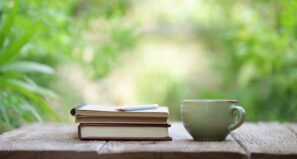 Coffee cup and journal with plants behind them