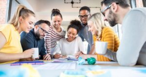 Group of individuals brainstorming on table with papers and coffee