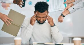 Person overwhelmed with people putting papers and times and phones in his face