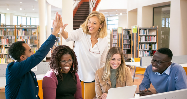 Teacher working with a group of students in a library