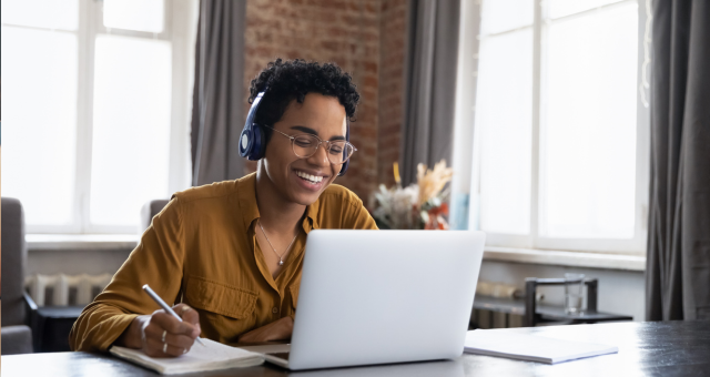 College student wearing glasses and headphones participating in an online class