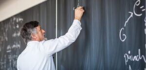 Male professor writing on a chalkboard