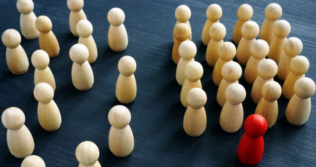 wooden carved people in two groups, one that is disorganized and the other organized into rows