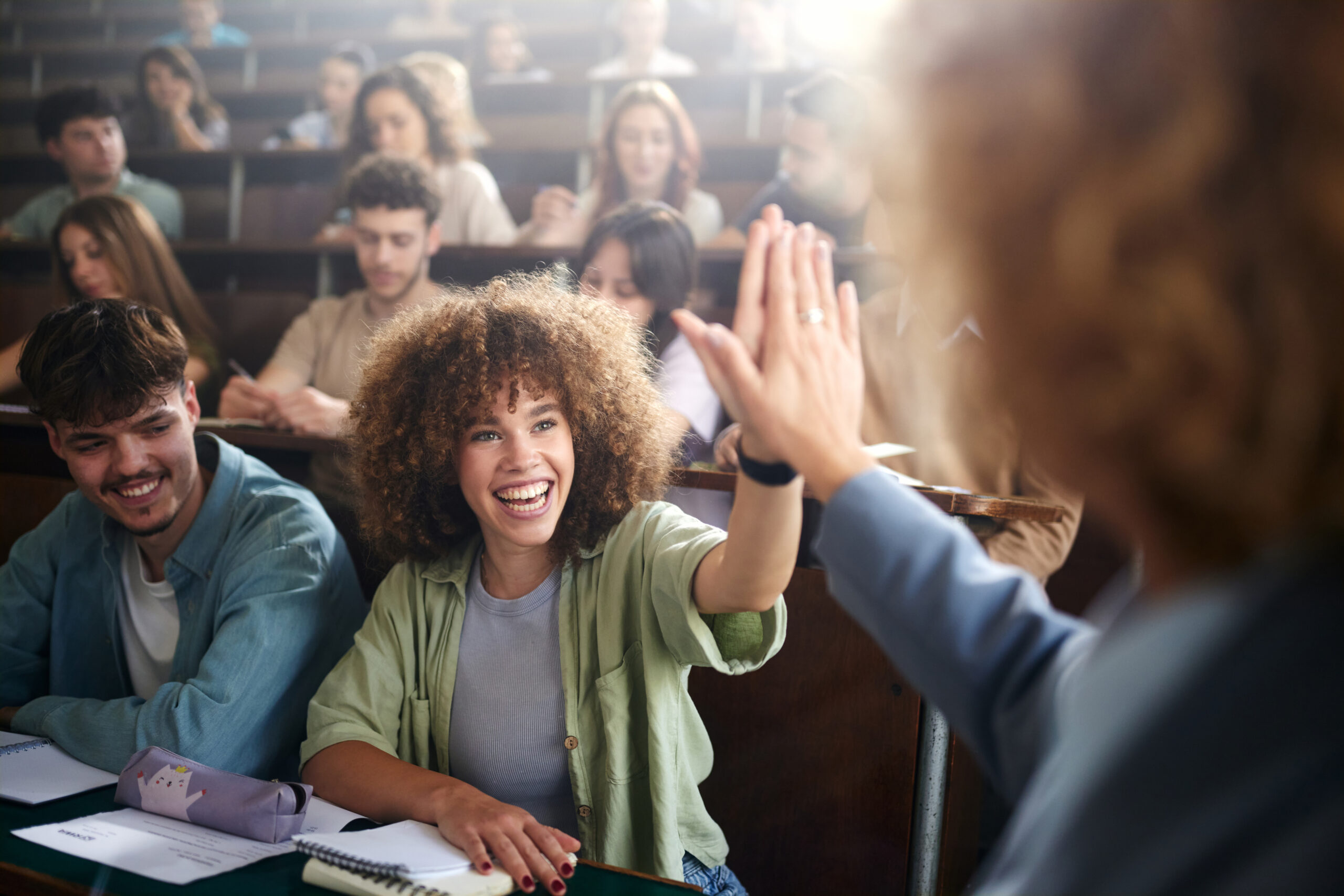 Happy student giving high-five to her professor on a class at lecture hall