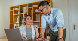 woman-and-man-at-desk-with-laptop-smiling-and-discussing