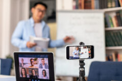 E-Learning. Unrecognizable Asian Teacher Man Teaching Making Group Video Call With Distance Students Using Phone And Laptop Computer Indoor. Online Class, Internet And Education. Shallow Depth
