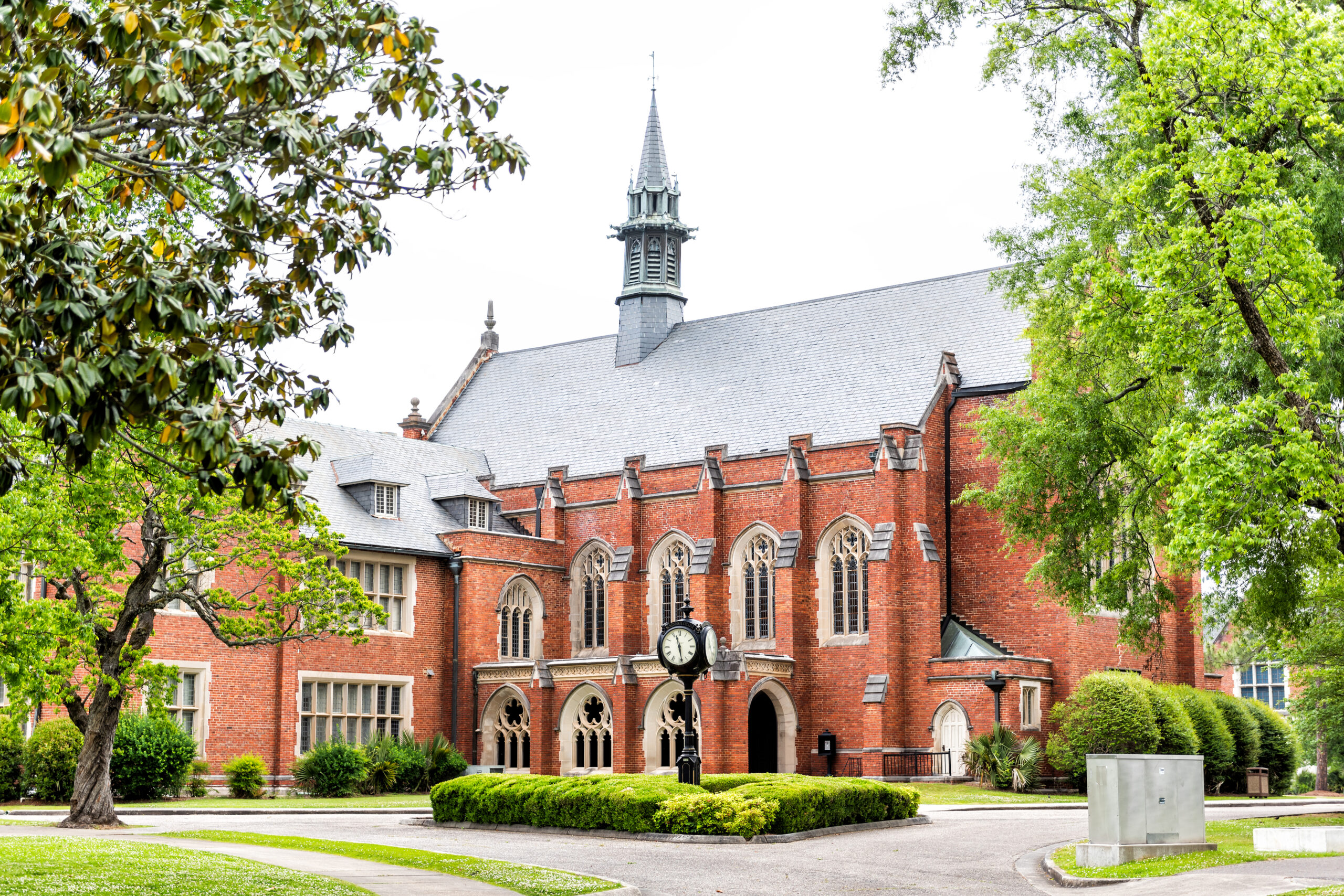 Exterior of private liberal arts Huntingdon College building in Alabama with old, brick, historic architecture, green park, clock