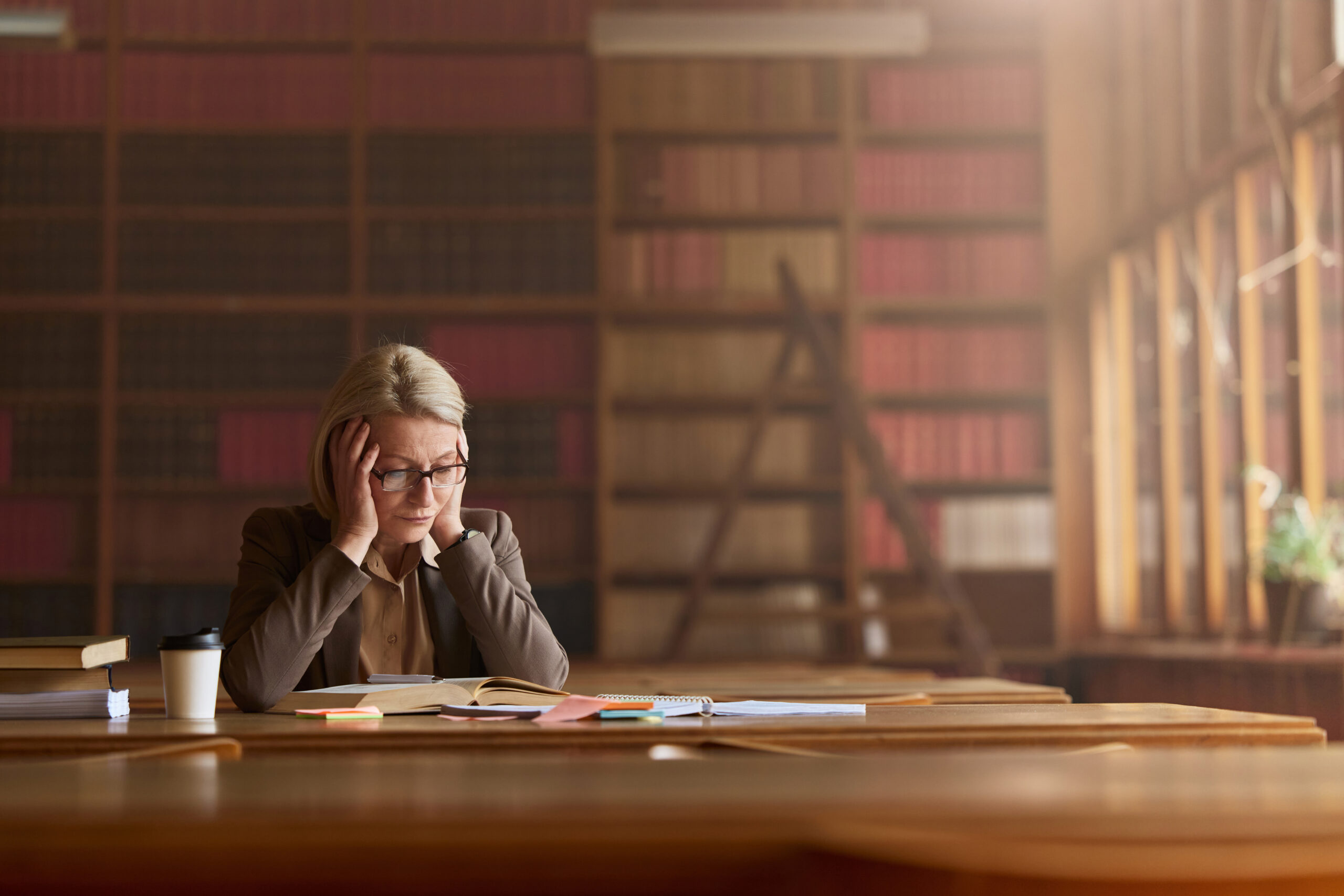 Displeased senior lawyer reading problematic rules of law in a book at library.