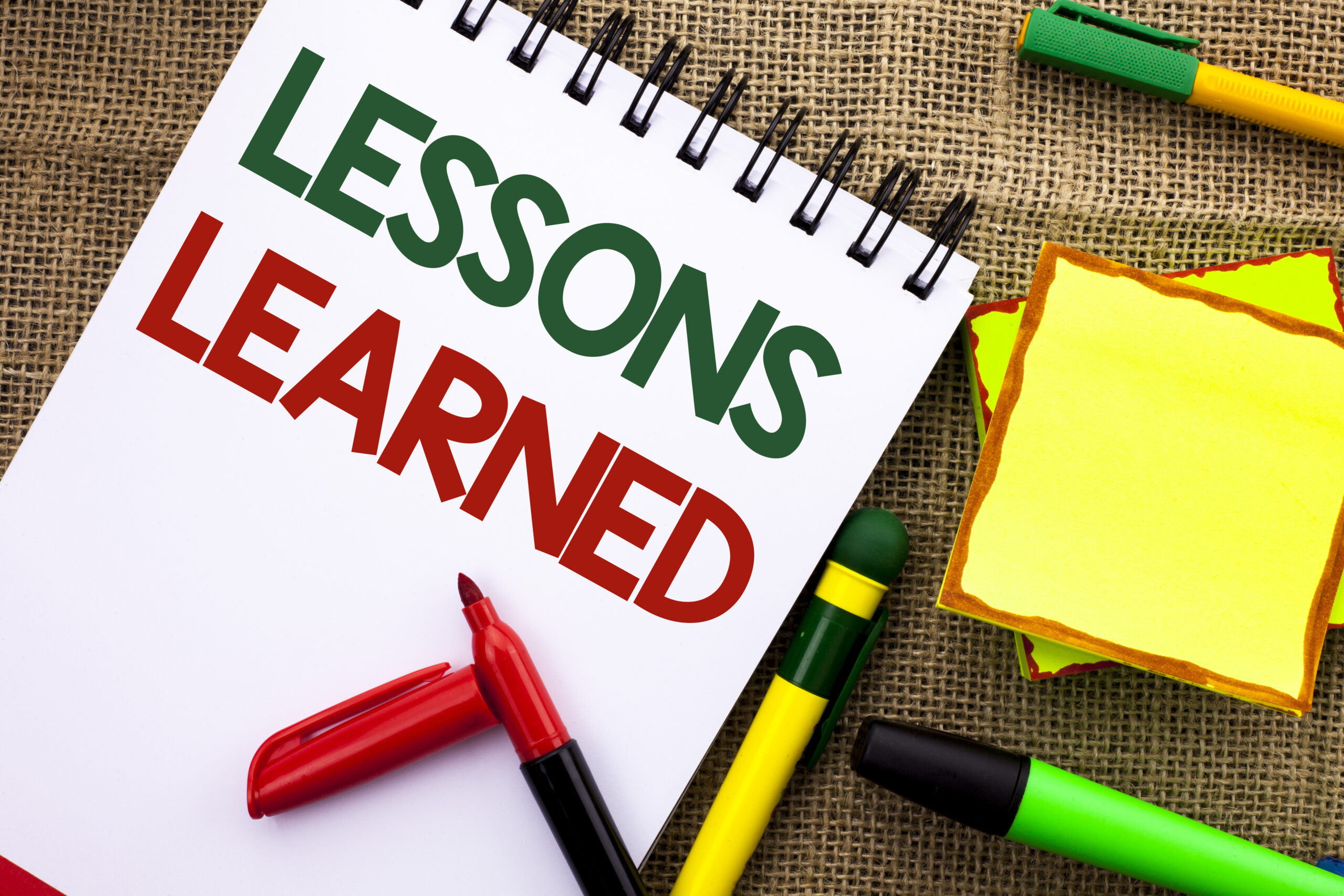 Writing note showing Lessons Learned. Business photo showcasing Experiences that should be taken into account in the future written Notebook Book the jute background Sticky Note Papers Pens