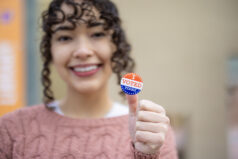 An Asian woman holding a "I Voted Today" sticker after voting.