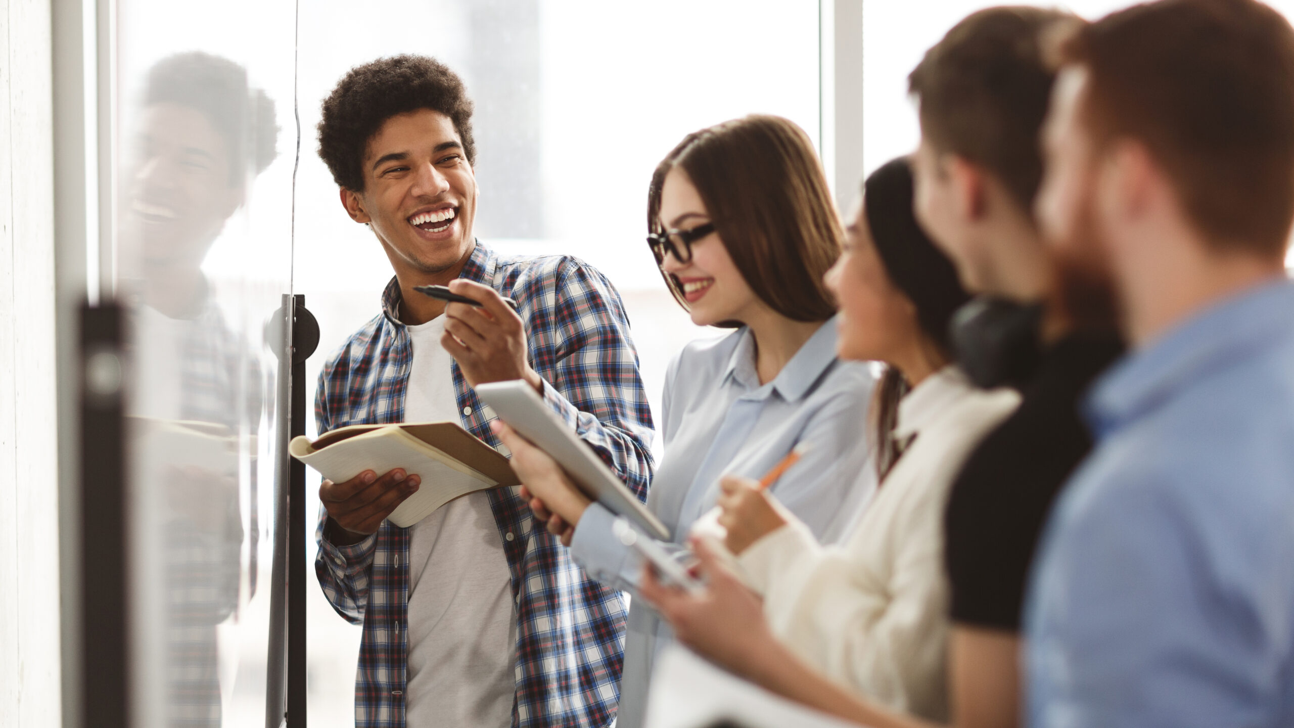 College students laughing, solving problems on whiteboard and taking notes