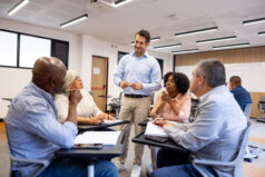Teacher talking to a group of other teachers doing professional development in a classroom.