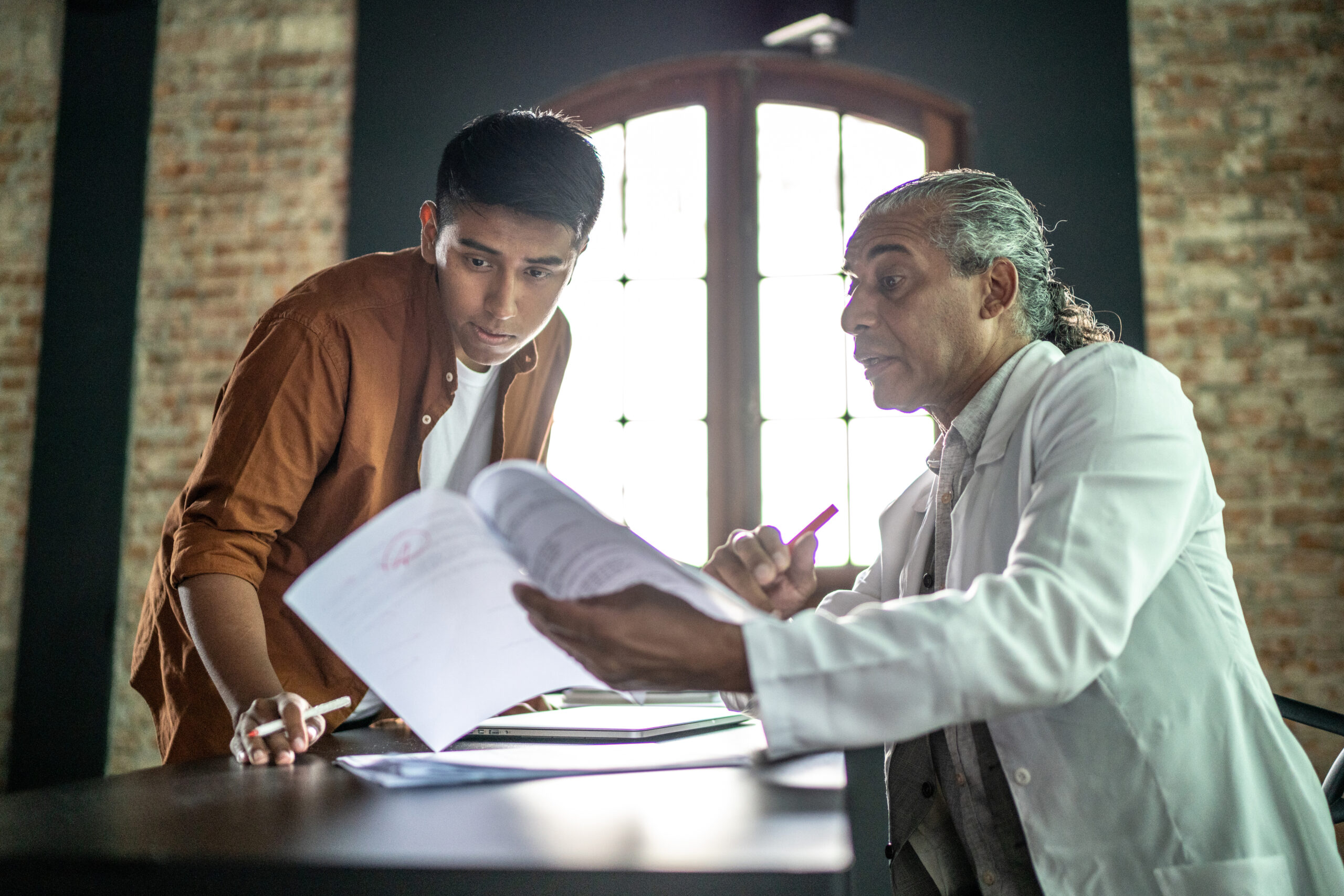 Teacher helping student on his desk, giving feedback on assignment
