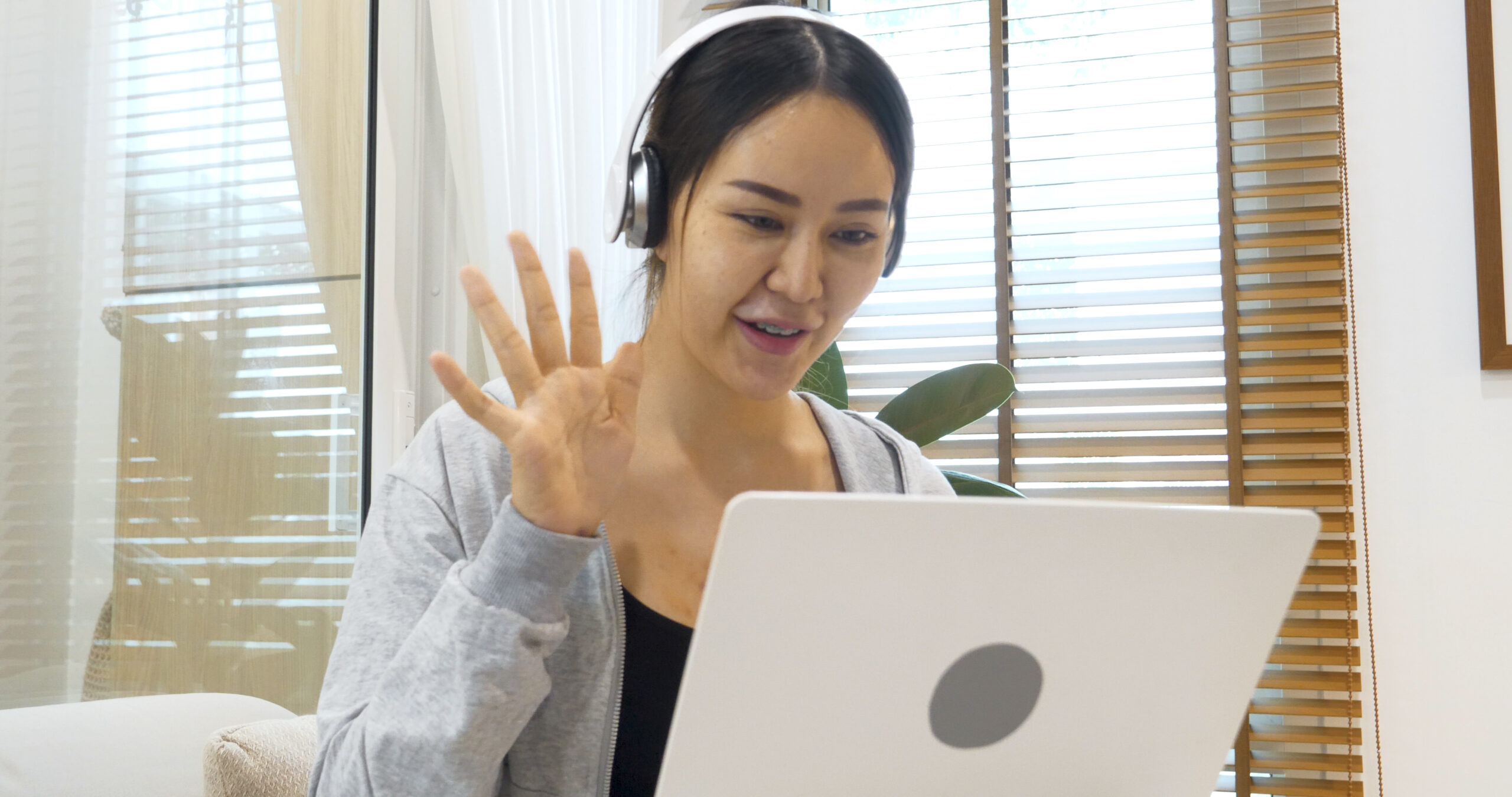 Happy asian woman working on her online course sitting on cozy sofa in living room at home. Smile Female asian people use laptop notebook computer headphones online course from home watching video